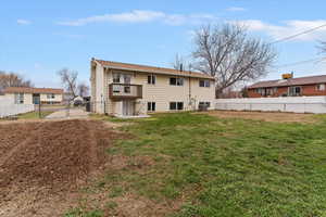 Back of house with a fenced backyard, a balcony, and a gate