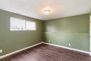 Spare room featuring dark wood-type flooring and a textured ceiling