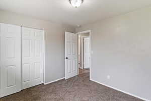Unfurnished bedroom featuring a closet and dark carpet