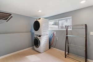 Laundry area with stacked washer / drying machine, light floors, recessed lighting, and a textured ceiling