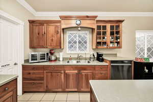 Kitchen featuring dishwasher, light countertops, ornamental molding, light tile patterned flooring, and wood finish cabinetry