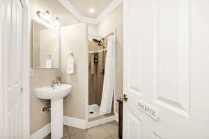 Full bath featuring a stall shower, crown molding, and light tile patterned floors