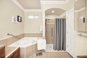 Full bathroom featuring a garden tub, crown molding, a stall shower, light tile patterned floors, and vanity