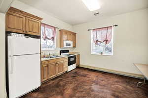 Kitchen featuring white appliances, light countertops, wood finish cabinetry, and concrete flooring