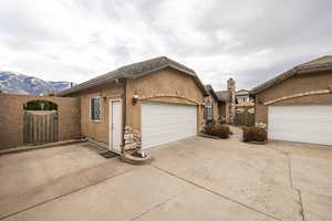 View of front of house with stucco siding, a gate, driveway, a garage, and a chimney