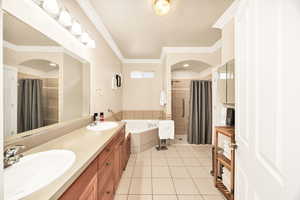 Full bath with double vanity, a bath, a stall shower, light tile patterned flooring, and ornamental molding