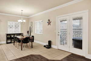 Dining space featuring light tile patterned floors, ornamental molding, and hanging lights