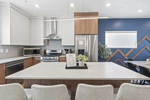 Dual tone kitchen featuring modern cabinets, stainless steel appliances, a kitchen breakfast bar, a kitchen island, and dual tone cabinetry