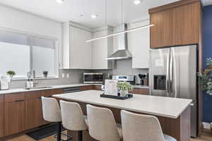 Two tone kitchen with modern cabinets, a kitchen breakfast bar, stainless steel appliances, two tone color scheme, and a center island