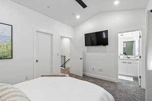 Bedroom featuring dark colored carpet, lofted ceiling, ensuite bath, ceiling fan, and recessed lighting
