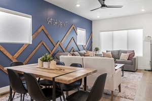 Dining area with light wood-style flooring, ceiling fan, an accent wall, and recessed lighting