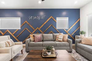 Living room featuring recessed lighting, an accent wall, and wood finished floors