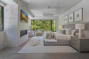Bedroom featuring multiple windows, wood finished floors, a fireplace, and recessed lighting