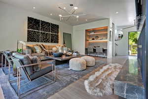 Living room with wood finished floors, a desk, and suspended lighting