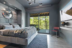 Bedroom featuring access to exterior, light wood finished floors, suspended lighting, and an accent wall