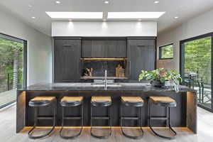Kitchen featuring modern cabinets, dark wood finish cabinets, light wood-style flooring, recessed lighting, and a large island
