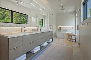 Bathroom with double vanity, a freestanding tub, a shower stall, tile walls, and recessed lighting