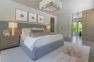 Bedroom with light wood-style floors, access to outside, and a chandelier