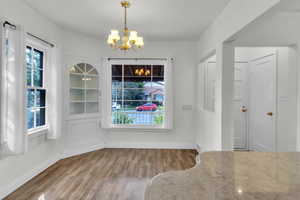 Unfurnished dining area featuring dark wood-type flooring and a chandelier