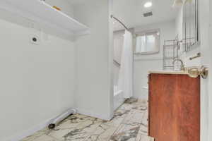 Laundry area with baseboards and light marble finish floors