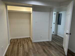 Unfurnished bedroom with a closet, dark wood-style floors, and electric panel