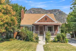 View of front of house featuring a porch, a front lawn, a chimney, and brick siding