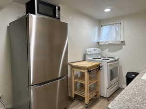 Kitchen featuring stainless steel appliances, light wood-style floors, a textured wall, and recessed lighting