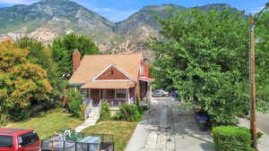 View of front of home with a porch, a chimney, a mountain view, a front lawn, and brick siding