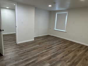 Empty room featuring dark wood-style floors, recessed lighting, and a smoke detector