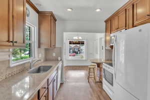 Kitchen featuring backsplash, white appliances, dark wood-style floors, and wood finish cabinetry