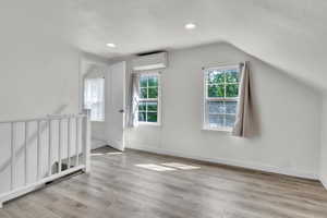 Bonus room with light wood-type flooring and lofted ceiling