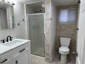Full bath with vanity, a stall shower, and light tile patterned flooring