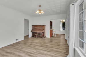 living area with suspended lighting and light wood-type flooring