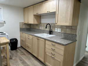 Kitchen with light wood finish cabinets, dark countertops, tasteful backsplash, and dark wood-style floors