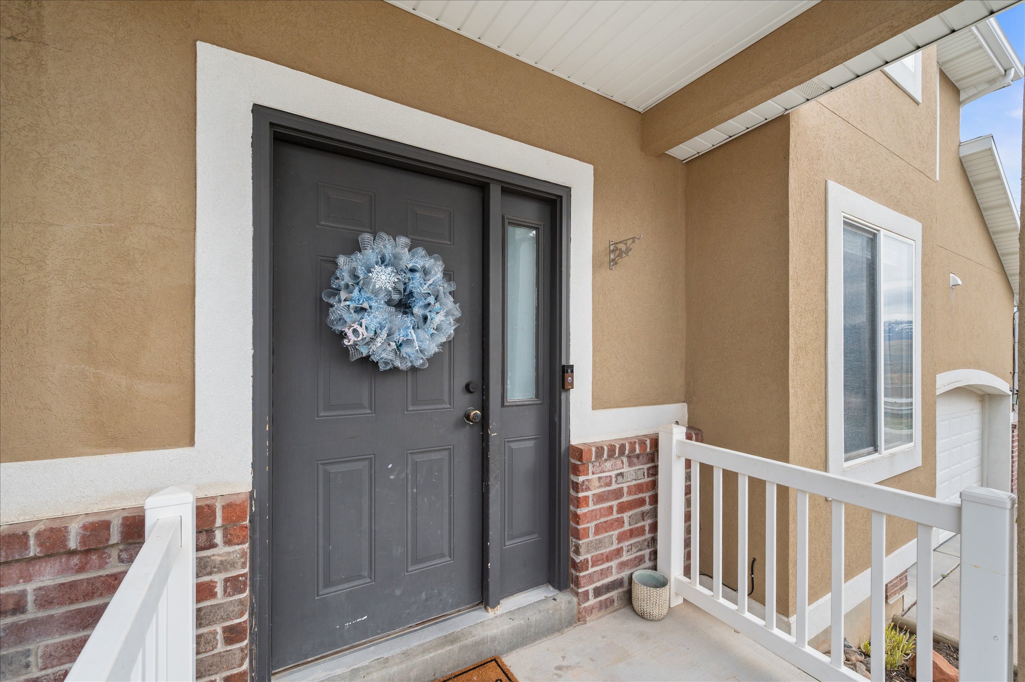 Property entrance featuring brick siding, stucco siding, and covered porch