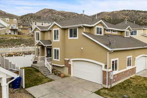 Traditional-style house featuring brick siding, stucco siding, concrete driveway, a garage, and a mountain view