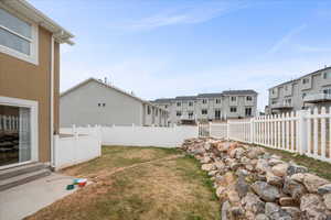 Fenced backyard with a residential view, entry steps, and a patio area