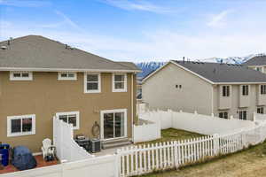Rear view of house with a fenced backyard, stucco siding, and a mountain view