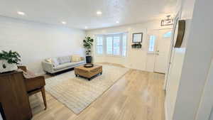 Living area featuring light wood-finish flooring, recessed lighting, and a prominent shiplap accent wall