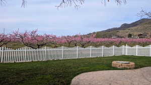 Fenced yard with an outdoor fire pit, a patio, and a mountain view View of mountain backdrop with season orchard in full bloom.