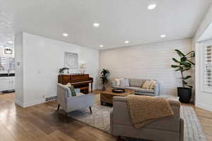 Living room with light wood-style flooring, recessed lighting, a textured ceiling, and an accent wall