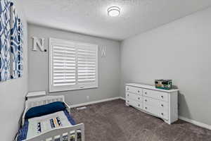Bedroom featuring a textured ceiling and dark colored carpet