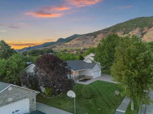 Ranch-style residence featuring a two-car garage, mature landscaping, and a mountain backdrop