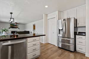 Kitchen with stainless steel appliances, white cabinets, a fireplace, a ceiling fan, and dark wood-style floors