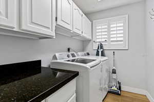Laundry room featuring light wood-style floors, washer and dryer, and cabinet space