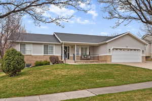 Single story home featuring covered porch, brick siding, a front lawn, and an attached garage