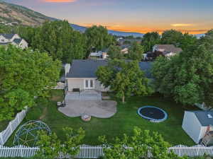 Expansive rear yard featuring a concrete patio, a built-in fire pit, and a lush green lawn
