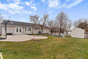 Rear view of house with a patio, a storage shed, french doors, a trampoline, and a fire pit