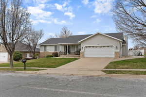Ranch-style home featuring covered porch, a garage, driveway, stucco siding, and brick siding