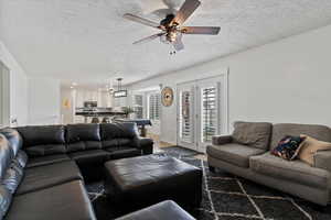 Living room with a textured ceiling, a ceiling fan, and recessed lighting